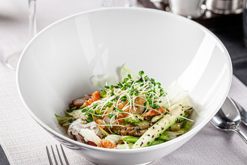 The concept of modern Vietnamese cuisine. Salad of rice noodles, iceberg lettuce, fried zucchini, green onions and squid. Beautiful serve in the restaurant.