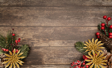 Christmas fir tree with gold poinsettie and berries on wooden background