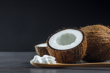 Organic natural whole and cracked coconut fruit and pieces of coconuts in wooden spoon on rustic...