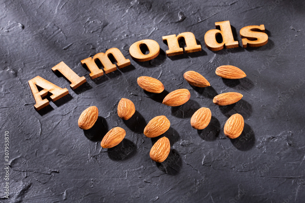 Poster prunus dulcis - peeled almonds. almonds word in wooden letters