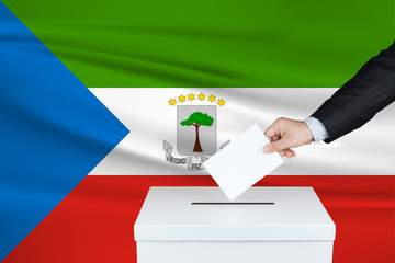 Election in Equatorial Guinea. The hand of man putting his vote in the ballot box. Waved Equatorial...
