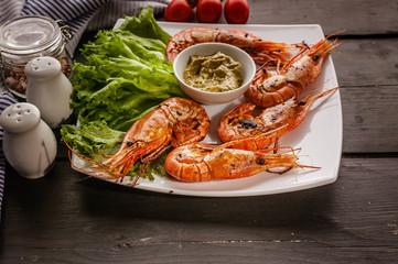 Close-up Grilled prawns with garlic and lemons on a white plate with lettuce