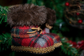 Cozy Christmas tree with traditional decorations. Vintage Christmas-tree decorated with Santa Claus woolen tartan boots.