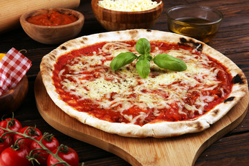 Pizza with tomatoes, mozzarella cheese, basil. Delicious italian pizza on wooden pizza board.