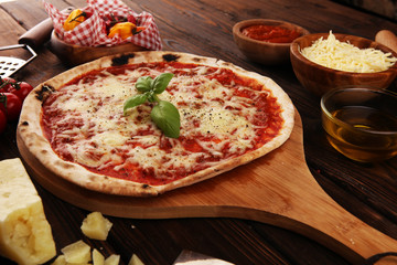 Pizza with tomatoes, mozzarella cheese, basil. Delicious italian pizza on wooden pizza board.