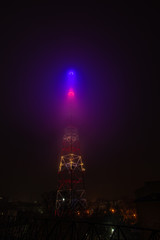 TV tower in the fog in the night city