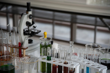Chemical laboratory glassware and blurred Laboratory Microscope on the background.
