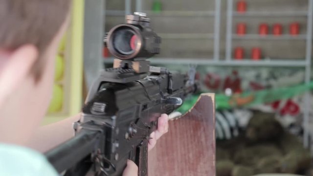 Caucasian teenage boy aiming with pneumatic rifle in shooting gallery, range