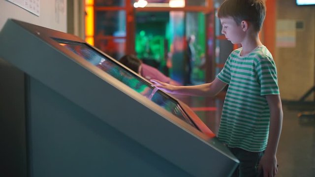 Distance school. Online School. Home education during quarantine of coronavirus infection COVID-19. Children make a purchase at the children center through a large touch screen.