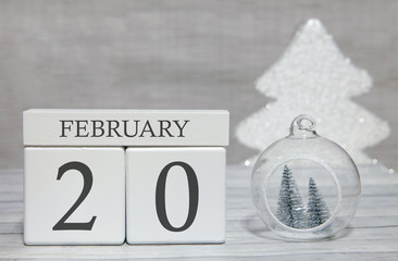 Cube shape calendar for February 20 on wooden surface and light background with empty space for text.