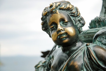 Old oxidized bronze statue of a boy with polished spots on his face as symbol of skin disease, pathology or condition such as vitiligo or psoriasis