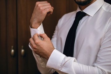 man fastens the sleeves of his shirt, close-up