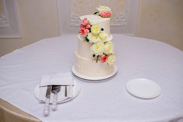 Beautiful wedding cake with creamy red roses, white delicious cake at the wedding