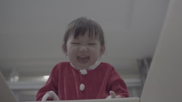 Merry Christmas and Happy Holidays! Cheerful cute child girl opening a Christmas present. Little kid having fun near Christmas tree indoors. View from inside of the box. slog3