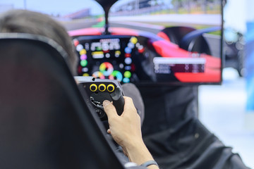 Close-up from back view and selective focus right hands of young man gamer who enjoying with racing game via gaming wheel controller on gaming monitor blurred background, entertain on leisure, e-sport © CHIRADECH