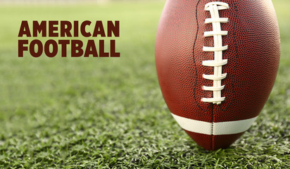Rugby ball and text AMERICAN FOOTBALL on green grass
