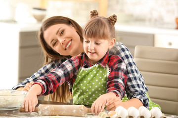 Happy mother and daughter cooking pastry at home