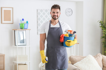 Male janitor with cleaning supplies in room