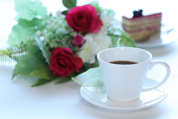 Fototapeta na wymiar コーヒーと赤いバラのスワッグとケーキ