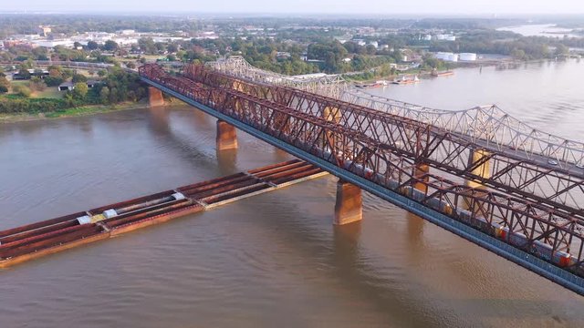Aerial of river barge under three steel bridges over the Mississippi River with Memphis, Tennessee background.