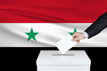 Election in Syria. The hand of man putting his vote in the ballot box. Waved Syria flag on...