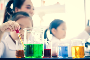 Beautiful researchers are teaching two girls who are interested in science in the laboratory.