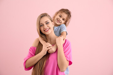 Happy woman and her little daughter on color background