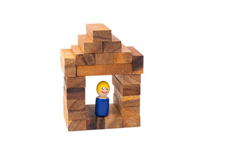 Obraz premium A wooden toy of a man stands and smiles in his beautiful wooden house on a white isolated background. The concept of a lonely happy man in a separate house.
