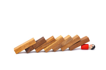 A wooden toy of a boy lies under a large number of obstacles in the form of wooden blocks on a white isolated background. The concept of overcoming difficulties and life hardships