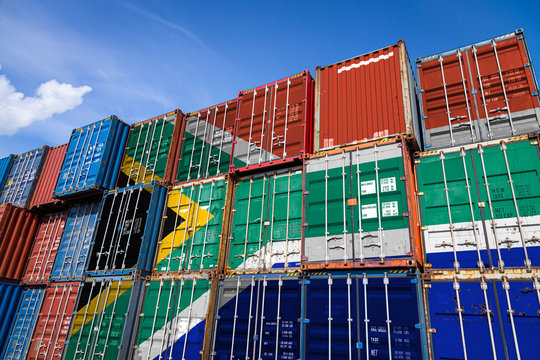 The national flag of South African Republic. on a large number of metal containers for storing goods stacked in rows on top of each other. Conception of storage of goods by importers, exporters