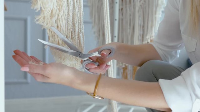 close-up creative woman scissors cuts ends of macrame