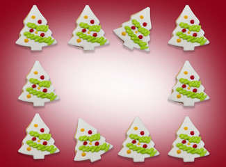 Background of glazed cookies in form of Christmas tree decorated with colorful frosting on red gradient background. with copy space at centerpoint