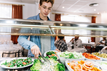 Boy taking salad from a self-service