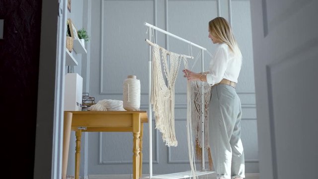 peeping through an open door as a woman artist weaves macrame in a workshop