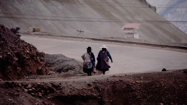 Indigenous Inca women walking along the dirt road of the mountains