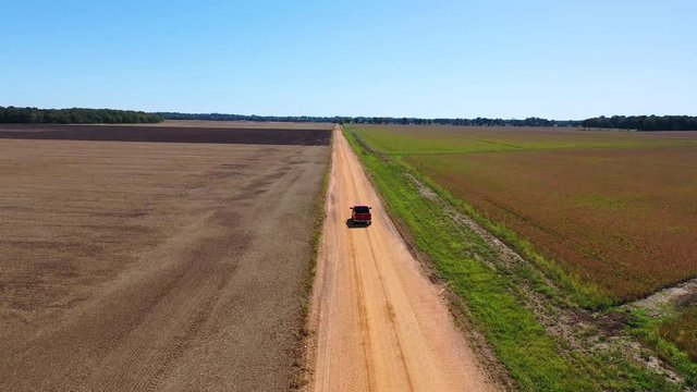 Aerial shot of a red pickup truck traveling on a dirt road in a rural farm area of Mississippi.