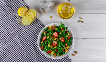 Salad with arugula, strawberries and mango with olive oil and lemon.