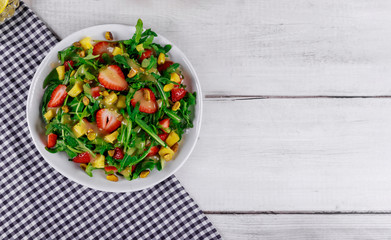 Green salad with fresh arugula, strawberry and pistachios on white background.
