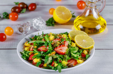 Healthy arugula salad with strawberries, pineapple and pistachios, sesame seeds, oil and lemon.