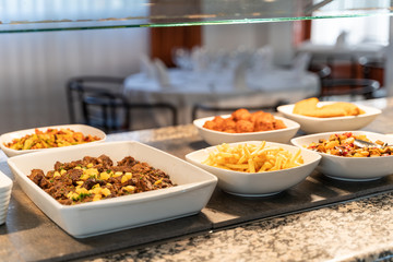 meat and potato stew tray together with other food trays in a self-service restaurant