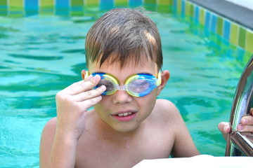 Boy child in water glasses in the pool. Children swimming in a private pool. Sports holidays.