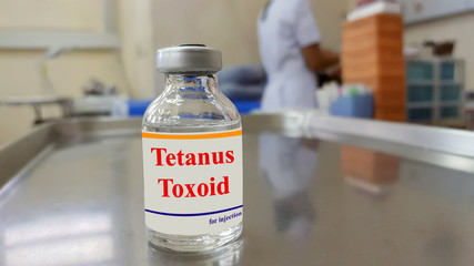 Medical bottle of Tetanus vaccine with blurred background of nurse dressing wound. Tetanus toxoid...
