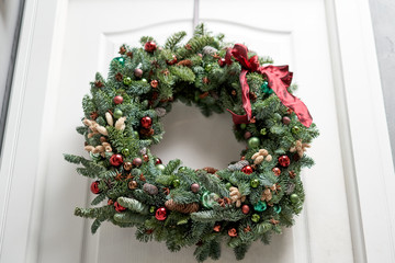 Beautiful Christmas wreath of fresh spruce on the white door. Entrance to the house. Christmas mood. Xmas tree.