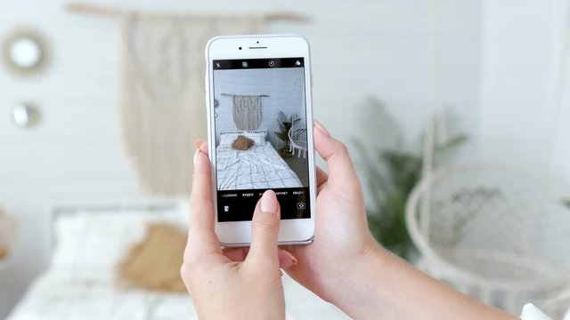 close-up woman photographs on the phone bedroom interior with macrame