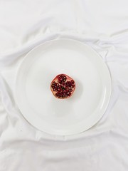 Top shot of half sliced pomegranate placed in a plate.