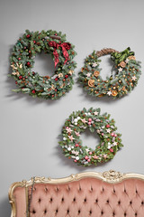 Three Beautiful festive wreaths of fresh spruce on the gray wall. Christmas mood. Xmas tree.