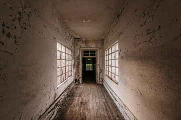 Corridor in abandoned building with old white ragged walls and windows bars