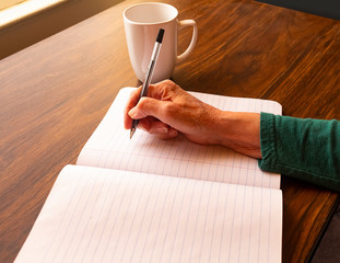 Senior hand writing in blank notebook
