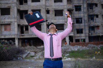Happy ecstatic Indian businessman or Student with files and both hands raised in the air . Man celebrating Joy after successful Project.