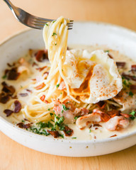 Pasta cream sauce with bacon and poached egg